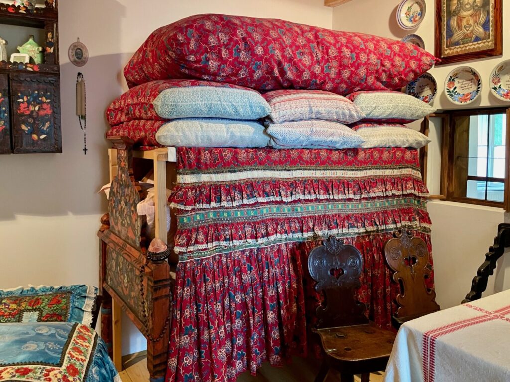 A Matyó bed piled high with embroidered quilts and pillows symbolising prosperity at the Matyó Museum in Mezőkövesd, Hungary