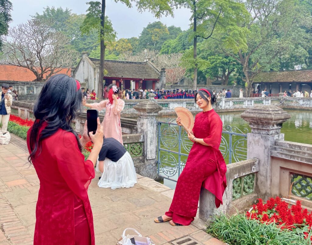 Vietnamese girls posing for photos in traditional dress at the Temple of Literature in Hanoi