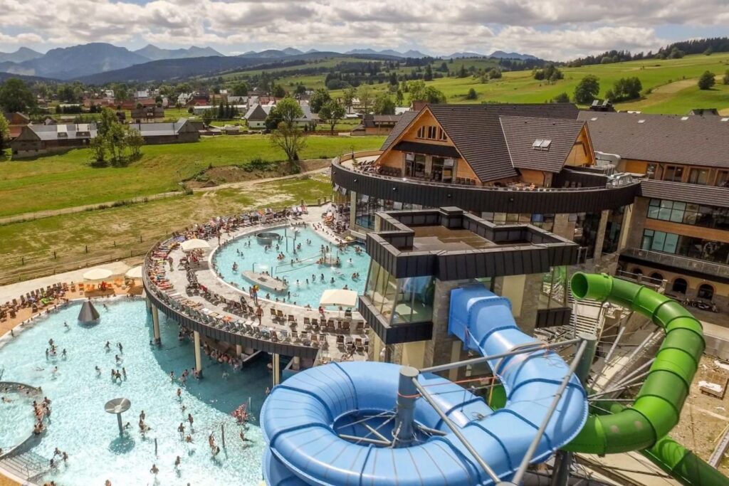 An aerial view of the Chochołów Thermal Baths in Poland, featuring slides and outdoor pools in the summer